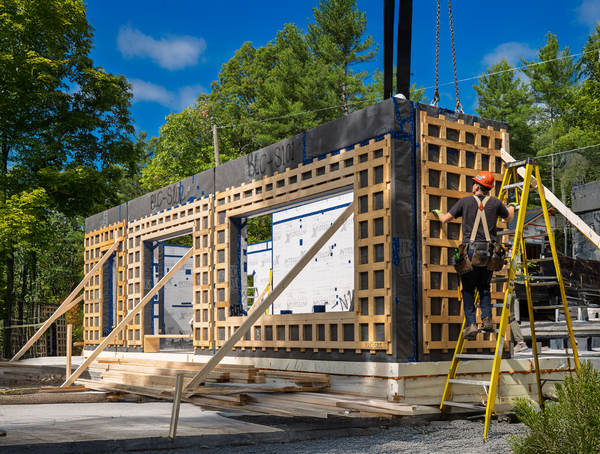 Panels standing on a finished slab as a Quantum crew member works from a ladder, the walls already enclosed.